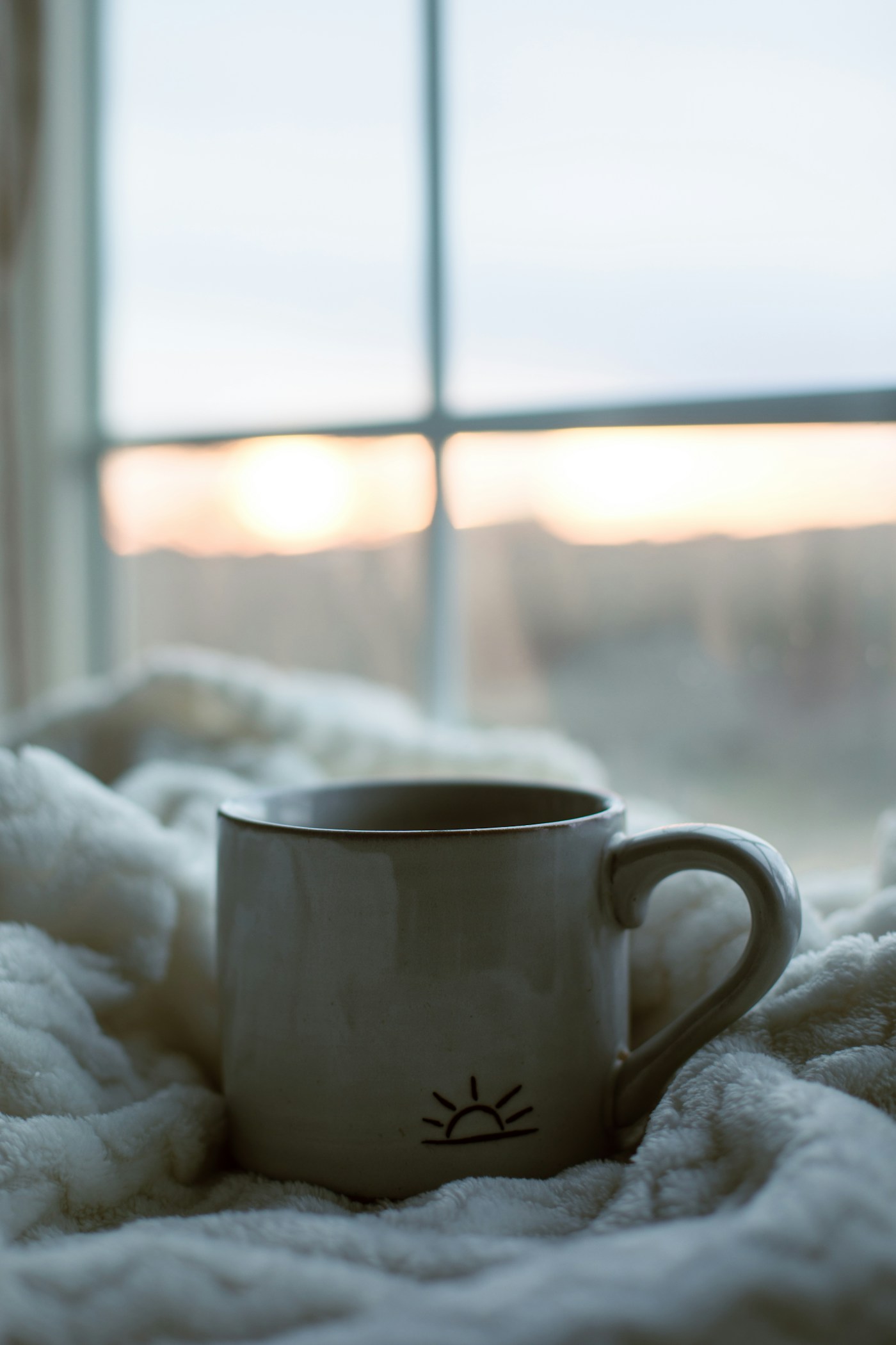 A warm cup of coffee beside a softly lit window